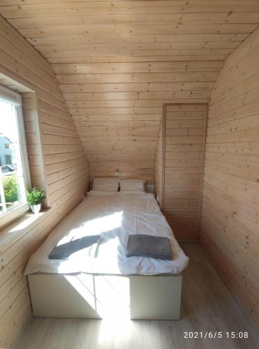 a large bed in a wooden room with a window at Plażowisko in Dębki