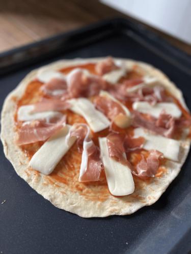 a pizza with ham and cheese on a pan at Arevaham Boutique Hotel in Stepʼanavan