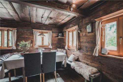 ein Esszimmer mit einem Tisch, Stühlen und Fenstern in der Unterkunft Knottn Hüttl, St. Pankraz/Ulten, Nähe Meran in St. Pankraz