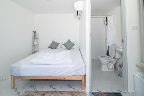 - une chambre blanche avec un lit et des toilettes dans l'établissement บ้านสายน้ำ วิลล่า, à Chiang Khan