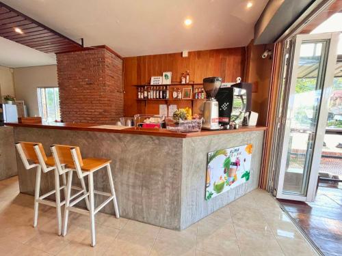 a kitchen with a bar with stools and a counter top at ALPHA Hostel Cafe&Bar in Ban Khlong Yai