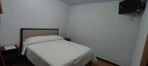 Un pequeño dormitorio con una cama blanca y una pared en HOTEL MARISOL, en Iquique