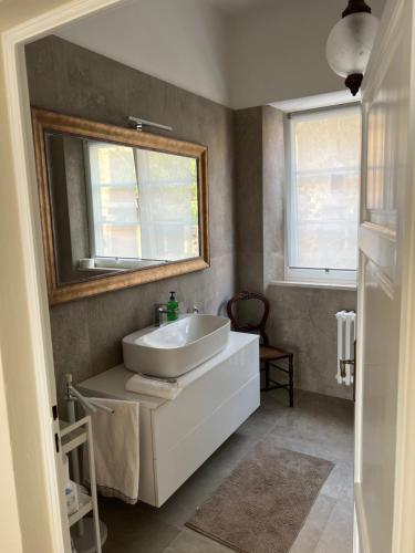 bagno con lavandino bianco e specchio di PANORAMA TERAZZA CON JACUZZI a Rivalto