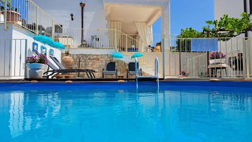 een zwembad met blauw water en blauwe parasols bij Valle D'Itria Trulli e Alcova Mikael in Cisternino