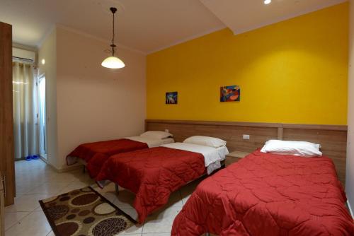 two beds in a room with a yellow wall at Hotel Restorant Halal Il Tramonto. in Vorë