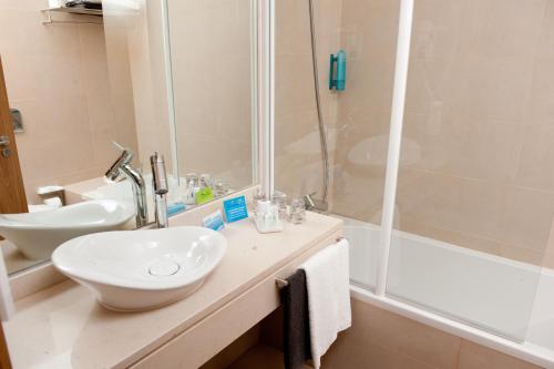 La salle de bains est pourvue d'un lavabo et d'une douche. dans l'établissement Atlantida Mar Hotel, à Praia da Vitória