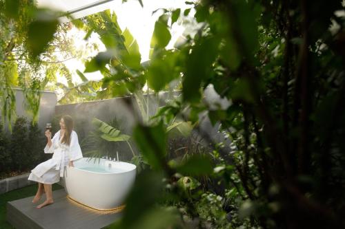 a woman sitting in a bath tub in a garden at Ioon Resort ไออุ่นรีสอร์ท in Sara Buri
