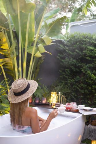 a woman sitting in a bathtub in a garden at Ioon Resort ไออุ่นรีสอร์ท in Sara Buri