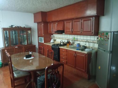 eine Küche mit Holzschränken, einem Tisch und einem Kühlschrank in der Unterkunft El paraíso in Guadalajara