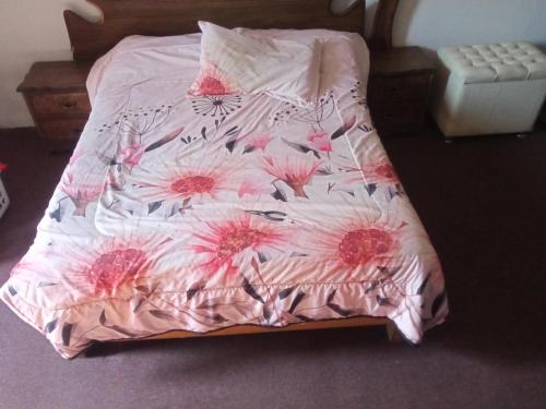 Una cama con un edredón rosa con flores. en El paraíso en Guadalajara