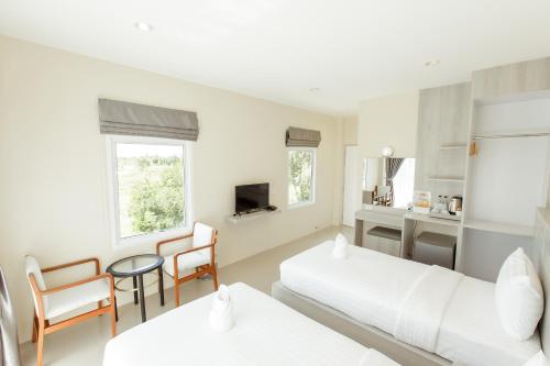 a white room with a bed and a table and chairs at Ioon Resort ไออุ่นรีสอร์ท in Sara Buri