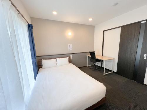 una camera d'albergo con letto e scrivania di BiBi Hotel 宮古空港前 SouthTower a Miyakojima
