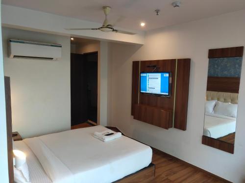 um quarto com uma cama e uma televisão na parede em Hotel Godrej Avenue VFS Global em Mumbai