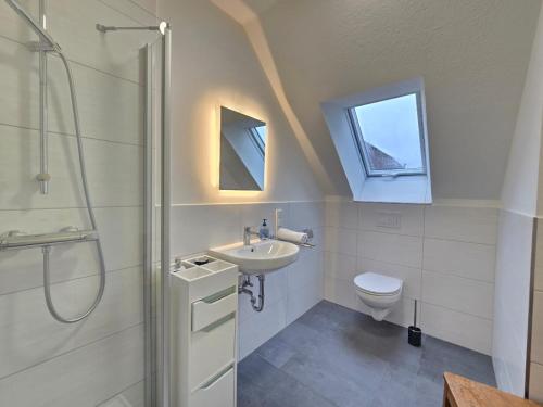 a bathroom with a sink and a toilet and a window at Friesenkate Steuerbord in Hagermarsch