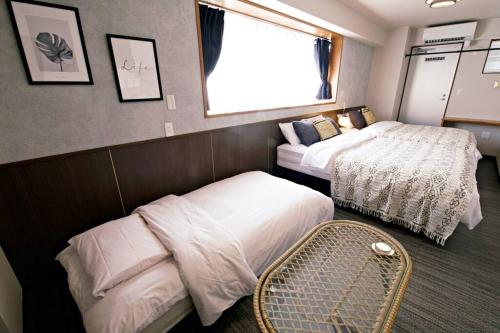 a hotel room with two beds and a window at TOMMY CONDOMINIUM WAKASA402 in Kume