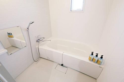 a white bathroom with a shower and a bath tub at TOMMY CONDOMINIUM WAKASA402 in Kume