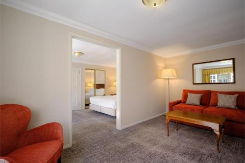 ダービーにあるDelta Hotels by Marriott Breadsall Priory Country Clubのリビングルーム(赤いソファ、ベッド付)