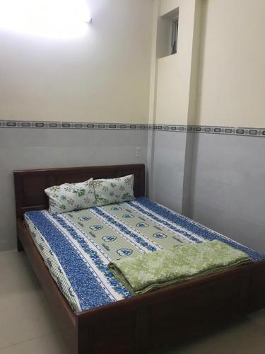 a bed with a blue and white quilt on it at Motel Liên Anh in Vung Tau