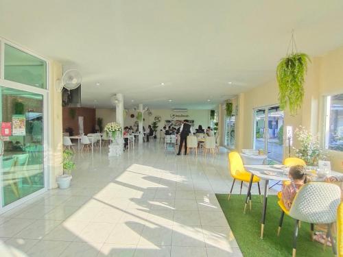 a room with tables and chairs and people in a building at Ioon Resort ไออุ่นรีสอร์ท in Sara Buri