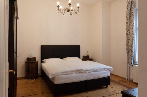 Schlafzimmer mit einem Bett mit weißer Bettwäsche und einem Kronleuchter in der Unterkunft Wohnen um die Jahrhundertwende in Brixen