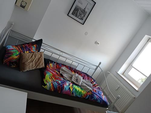 Una cama con una manta colorida y almohadas. en Stella's Monteurswohnungen en Crimmitschau