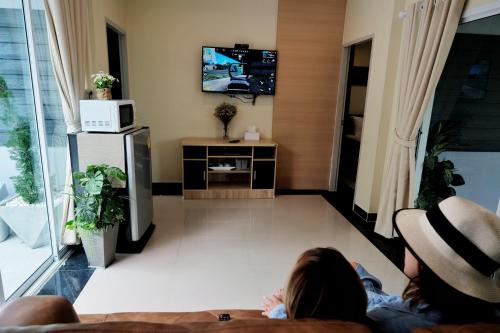 two people sitting on a couch in a living room at Ioon Resort ไออุ่นรีสอร์ท in Sara Buri