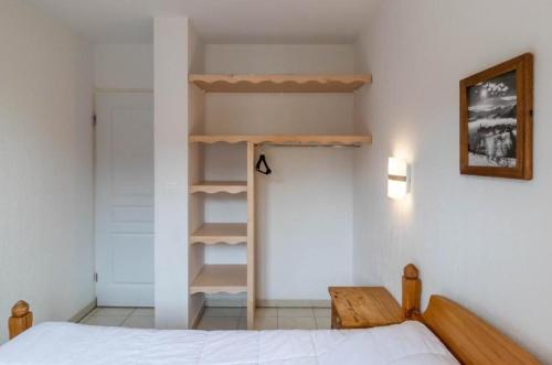 une chambre avec un lit et une étagère dans l'établissement APT T2 4 COUCHAGES dans RES. 4 * - BALCONS des AIRELLES (1800) coeur de station, aux Orres