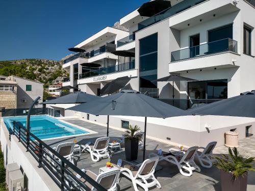 - un bâtiment avec une piscine, des chaises et des parasols dans l'établissement Villa Balmis House A, à Makarska