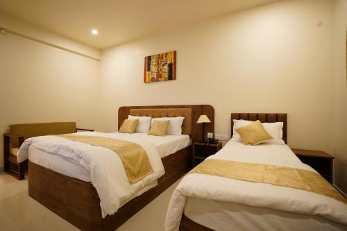 two beds in a hotel room with twoermottermott at DrizzleDrop Inn Chennai in Chennai