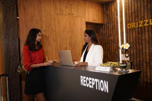 two women standing at a reception desk with a laptop at DrizzleDrop Inn Chennai in Chennai