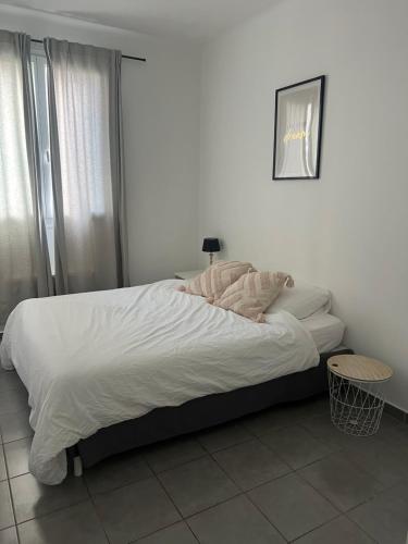 sypialnia z łóżkiem z białą pościelą i poduszkami w obiekcie Appartement quartier la Timone w Marsylii