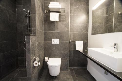 a bathroom with a toilet, sink, and bathtub at Bastion Hotel Tilburg in Tilburg