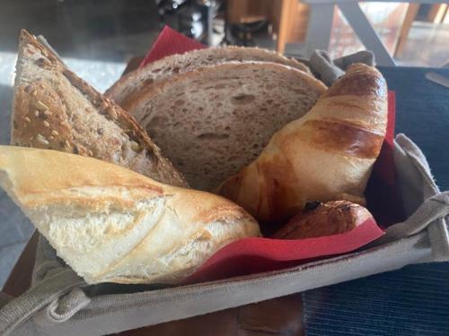 una cesta llena de diferentes tipos de pan en una mesa en Le Goupil, en Wavre