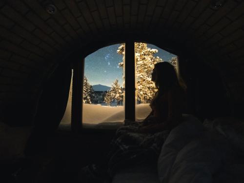 a woman sitting in a window looking at the snow at Eventyrhyttene i Jotunheimen in Stuttgongfossen
