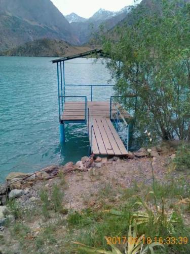 a dock on a lake with mountains in the background at ISKANDARKUL guest house in Kanchoch