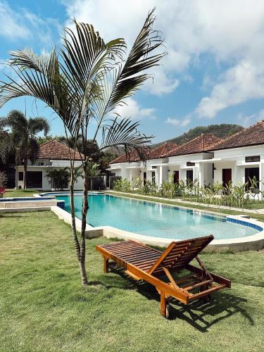 un banc à côté d'un palmier à côté d'une piscine dans l'établissement Nomada Villas, à Kuta Lombok