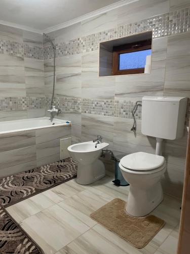 La salle de bains est pourvue de toilettes, d'un lavabo et d'une baignoire. dans l'établissement Casa Roșca, 