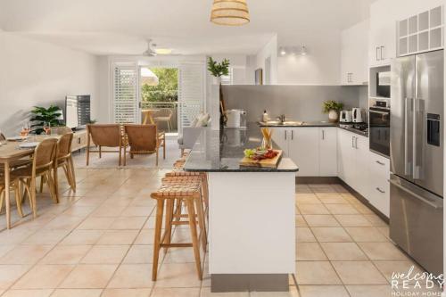 a kitchen and dining room with white cabinets and a table at Spacious Seaside Oasis on Dicky Beach in Caloundra