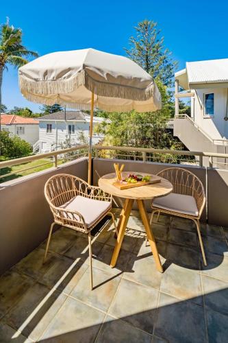 a patio with a table and two chairs and an umbrella at Spacious Seaside Oasis on Dicky Beach in Caloundra