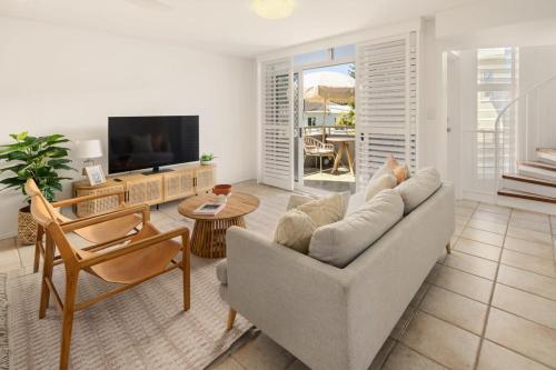 a living room with a couch and a tv at Spacious Seaside Oasis on Dicky Beach in Caloundra