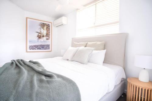 a white bedroom with a white bed and a window at Spacious Seaside Oasis on Dicky Beach in Caloundra