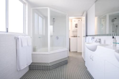 a white bathroom with a shower and a sink at Spacious Seaside Oasis on Dicky Beach in Caloundra