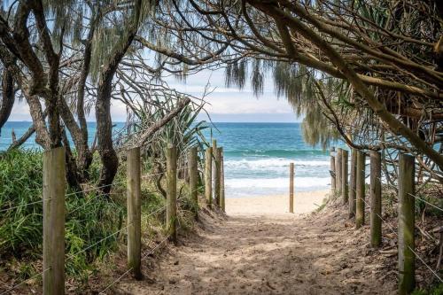 a path to the beach through a wooden fence at Spacious Seaside Oasis on Dicky Beach in Caloundra