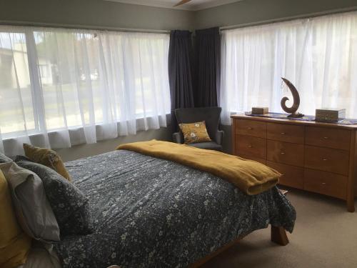 a bedroom with a bed and a dresser and windows at River Heights in Taupo