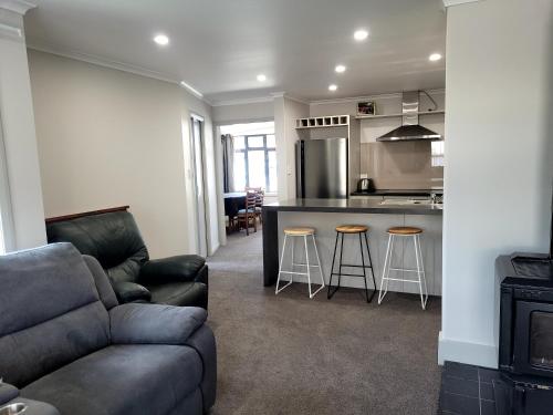 a living room with a couch and a kitchen at The Old Parsonage in Reefton