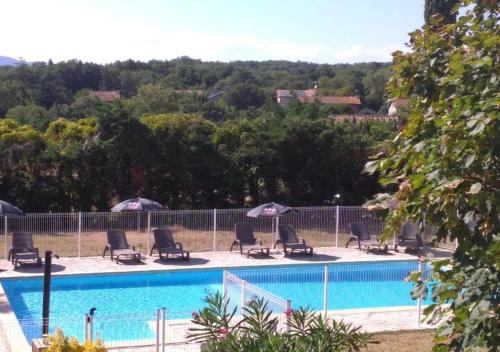 a pool with chairs and umbrellas next to a fence at Gites les Voyageurs in Vogüé