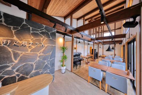 a dining room with a large stone wall at おそとのてらす　南アルプス in Minami Alps