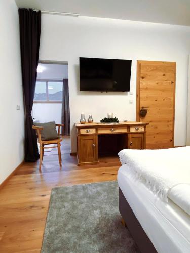 a bedroom with a television and a desk with a chair at s'pölven NEST in Bad Häring
