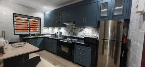 a kitchen with blue cabinets and a stainless steel refrigerator at Résidence Axel in Pointe-Noire