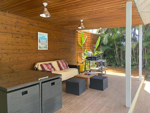 - une terrasse couverte avec un canapé et une table dans l'établissement La Kaz Pomme Cannelle, à La Rivière